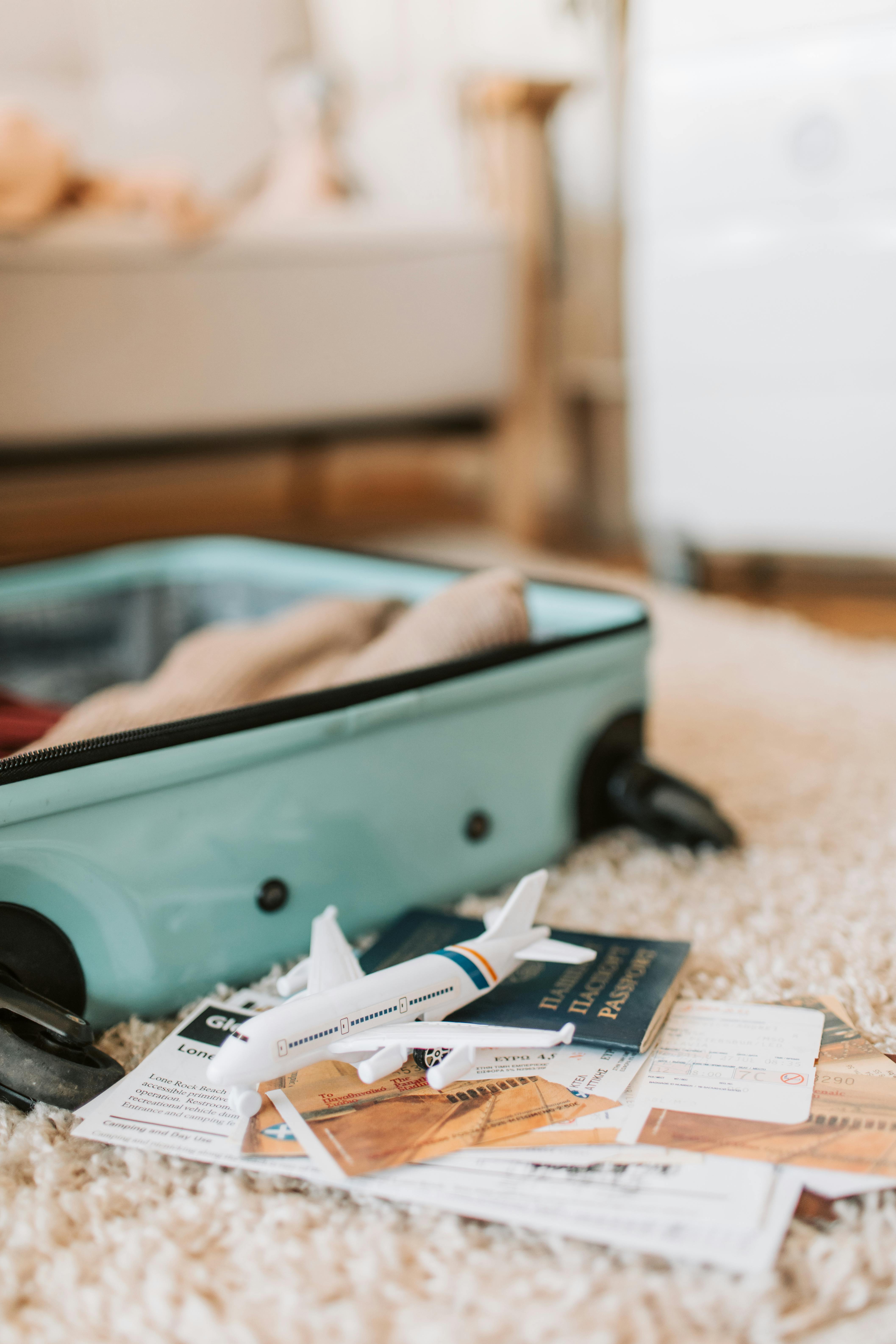 Travel preparation with teal suitcase, passport, toy airplane and travel documents